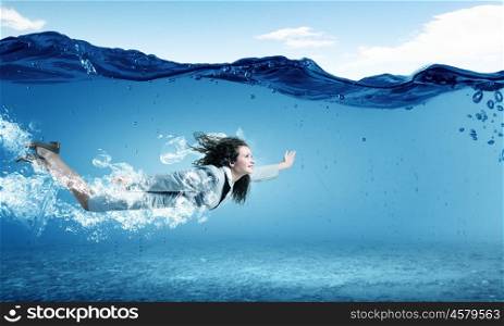 Young businesswoman in suit swimming in crystal blue water. Woman underwater