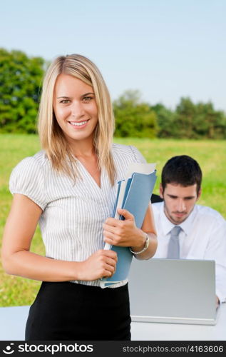 Young businesswoman in sunny nature with folders and male colleague