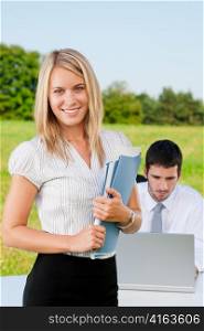 Young businesswoman in sunny nature with folders and male colleague