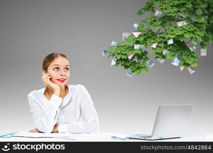 Young businesswoman in the office with money banknotes around her