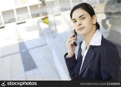 Young businesswoman is calling on mobile phone outdoor, somewhere in the downtow district.