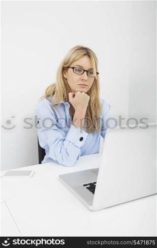 Young businesswoman looking at laptop in office
