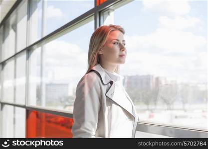 Young businesswoman looking through glass at railroad station