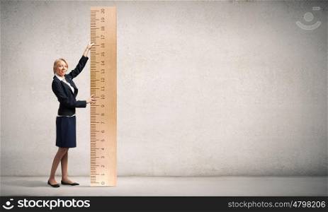 Young businesswoman measuring something with big ruler. Take measures