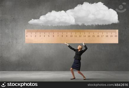 Young businesswoman measuring something with big ruler. Take measures