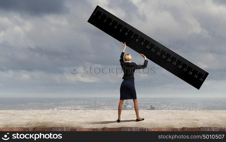 Young businesswoman measuring something with big ruler. Take measures