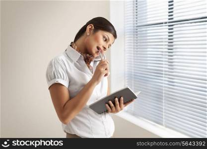 Young businesswoman on phone call while holding diary at office