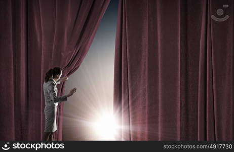 Young businesswoman opening stage curtain to another reality. Open new opportunities