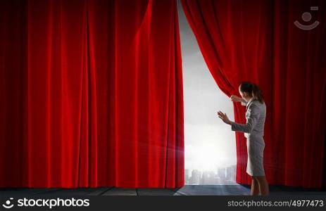 Young businesswoman opening stage curtain to another reality. Open new opportunities