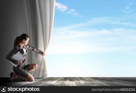 Young businesswoman opening stage curtain to another reality. Opened curtain