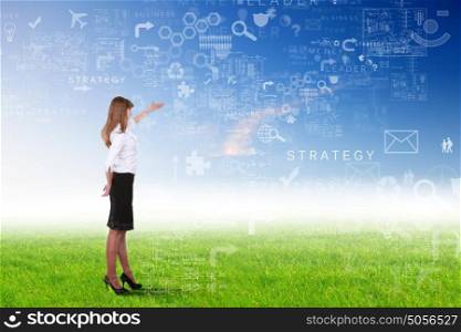 Young businesswoman outdoor with business symbols on the sky background