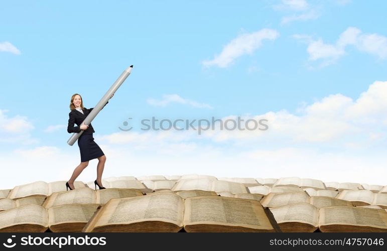 Young businesswoman pointing up with big pencil. Big professional