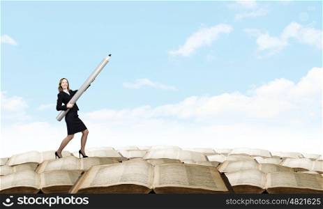 Young businesswoman pointing up with big pencil. Big professional