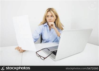 Young businesswoman reading document in office