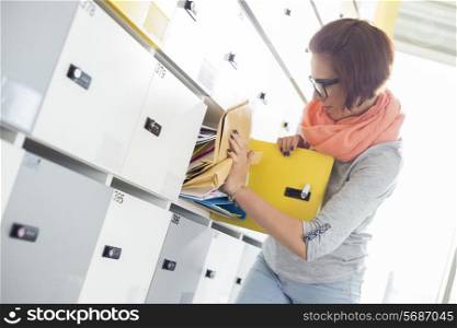 Young businesswoman removing file from locker at creative office