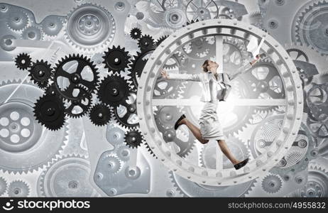 Young businesswoman running in wheel of gears mechanism. To turn as squirrel in wheel