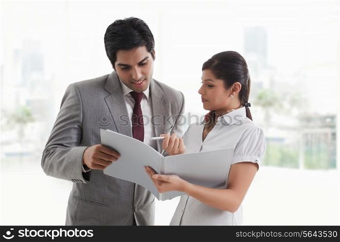 Young businesswoman showing document to businessman in office