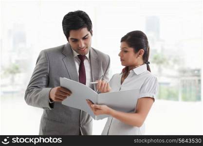Young businesswoman showing document to businessman in office