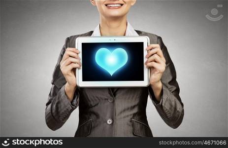Young businesswoman showing tablet pc against heart. Cardiology concept