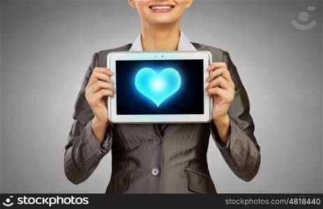 Young businesswoman showing tablet pc against heart. Cardiology concept