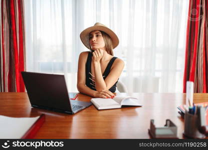 Young businesswoman sitting at the table in office and dreaming about a vacation