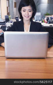 Young businesswoman sitting in front of laptop, portrait