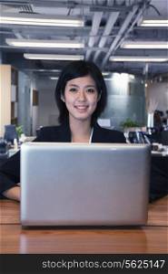 Young businesswoman sitting in front of laptop, portrait