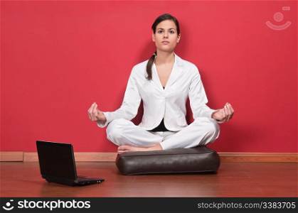 Young businesswoman sitting in yoga lotus position with laptop on the floor