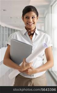 Young businesswoman smiling confidently while holding documents