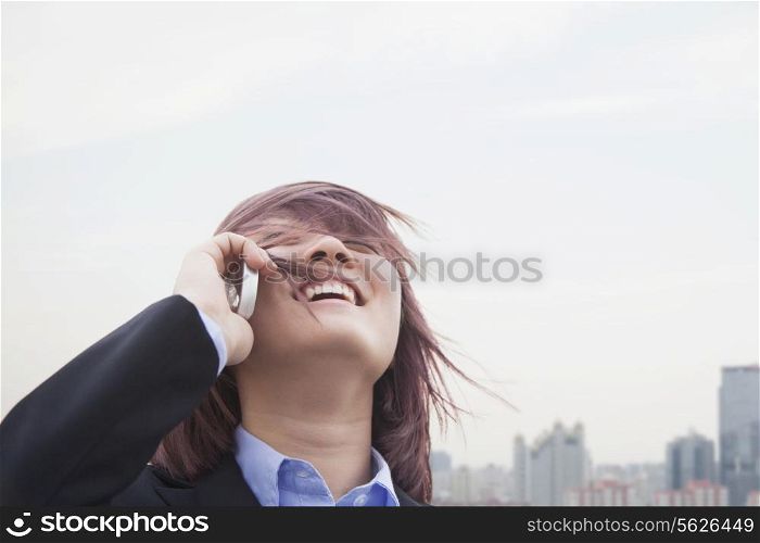 Young businesswoman smiling using her cell phone with hair blowing