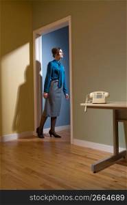 Young businesswoman standing in a doorway and looking up