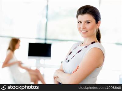 Young businesswoman standing in office with her collegue on the background