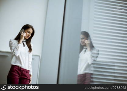 Young businesswoman standing in the office and  using mobile phone