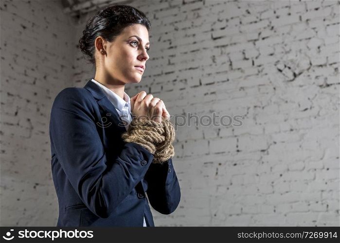 Young businesswoman standing with tied hands at office