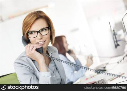 Young businesswoman talking on telephone at desk in office