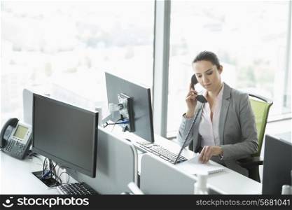 Young businesswoman talking on telephone in office