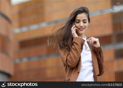 Young businesswoman talking with a smartphone in urban background. Beautiful woman wearing formal wear using smart phone.