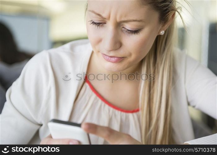 Young businesswoman text messaging through cell phone in office