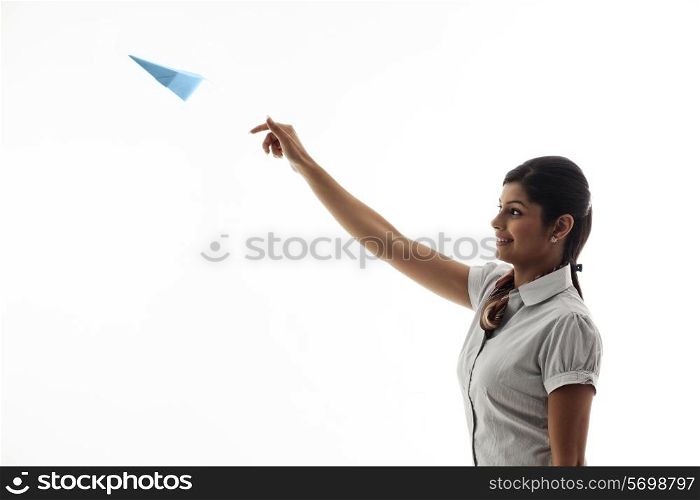 Young businesswoman throwing airplane on white background