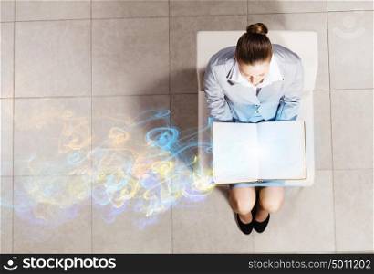 Young businesswoman. Top view of businesswoman sitting in chair and reading book