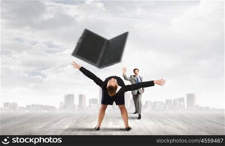 Young businesswoman trying to evade from thrown laptop
