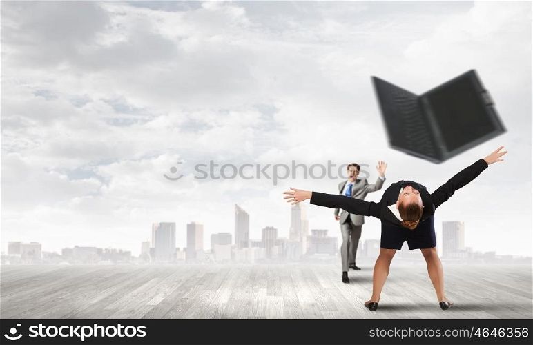Young businesswoman trying to evade from thrown laptop