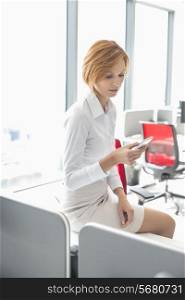 Young businesswoman using cell phone in office