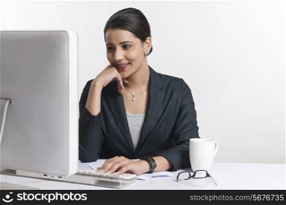 Young businesswoman using computer at desk against white background