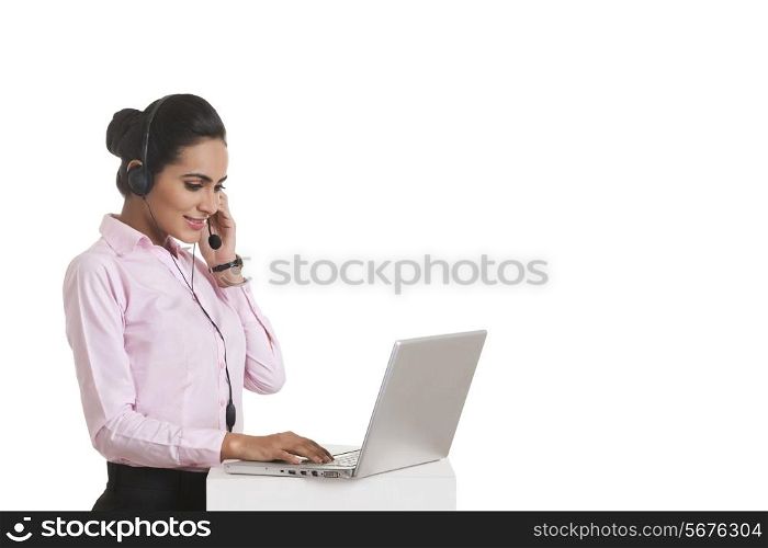 Young businesswoman using headset and laptop over white background