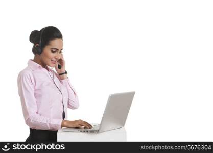 Young businesswoman using headset and laptop over white background