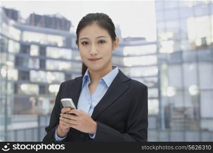 Young businesswoman using her phone, cityscape in background
