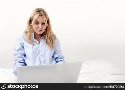 Young businesswoman using laptop in bed