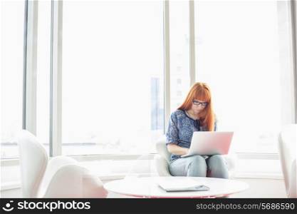Young businesswoman using laptop in creative office