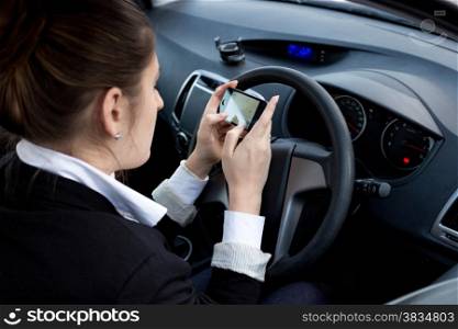 Young businesswoman using smartphone while driving car